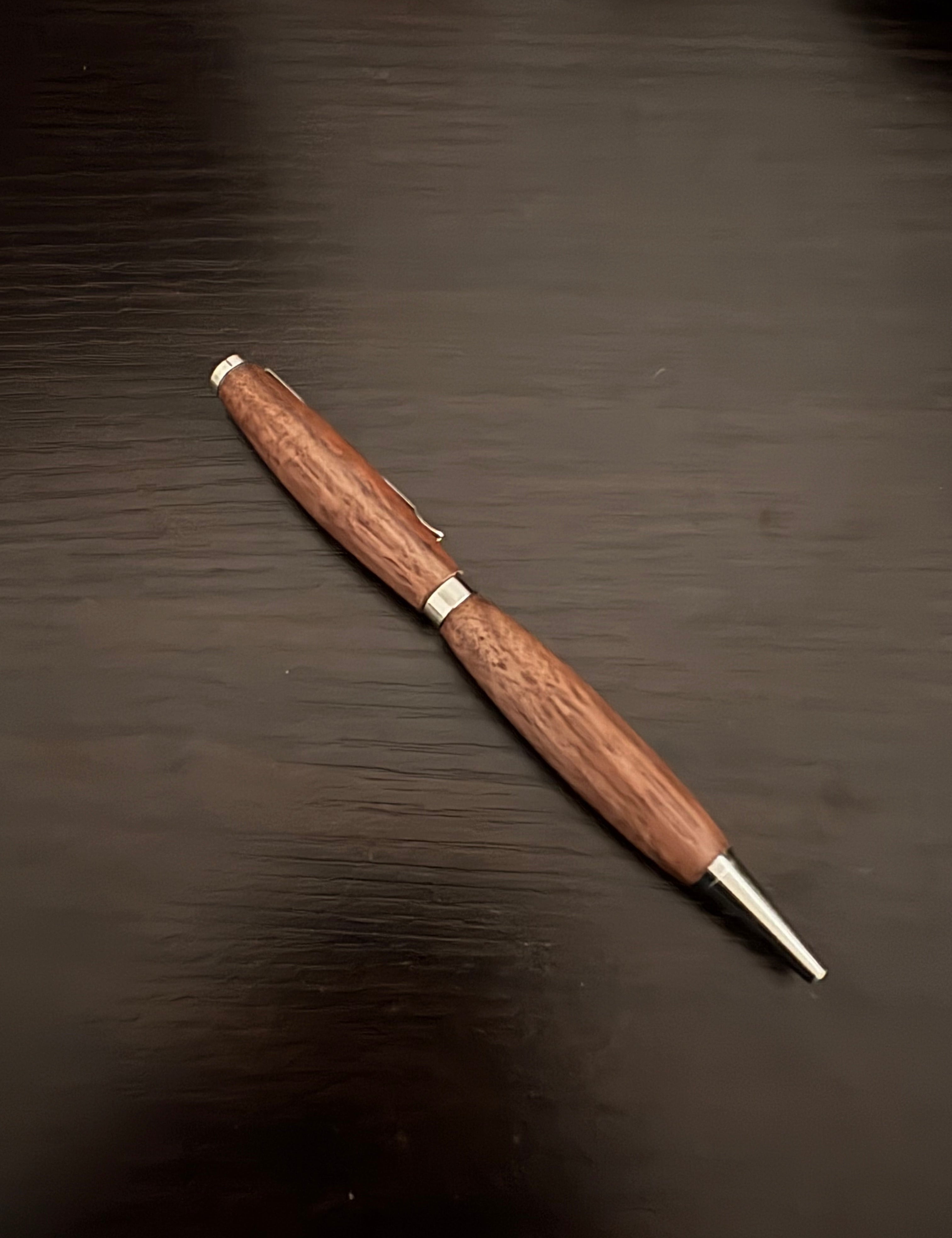Wooden pen with silver accents on a dark wooden surface