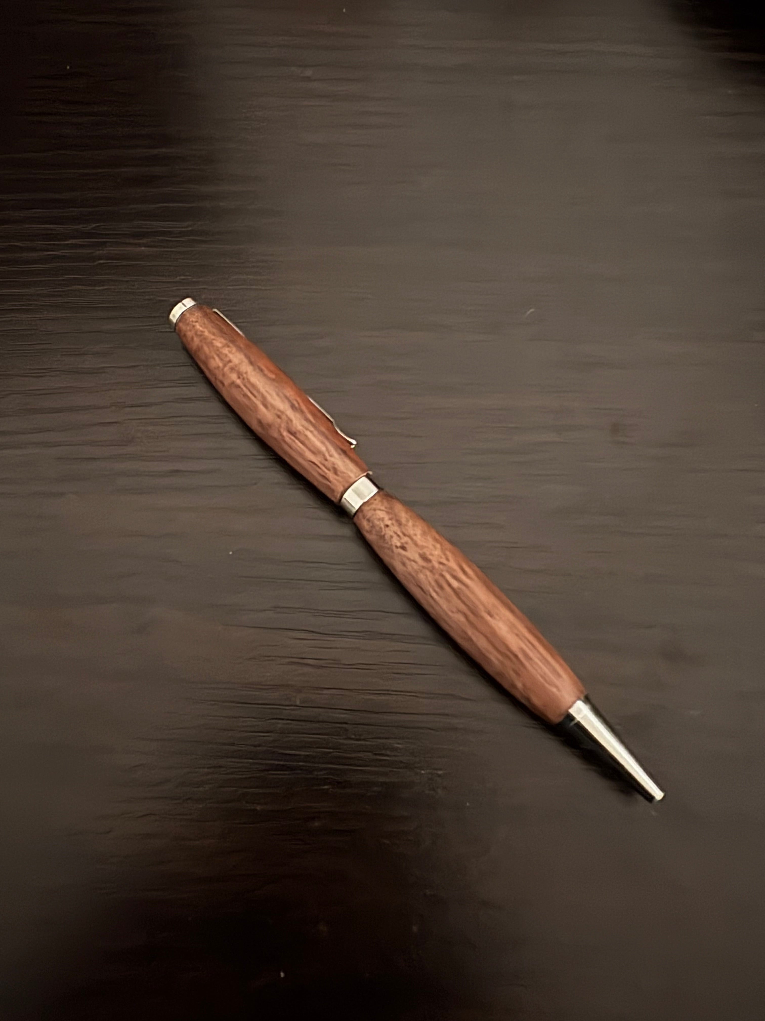 Wooden pen with silver accents on a dark wooden surface