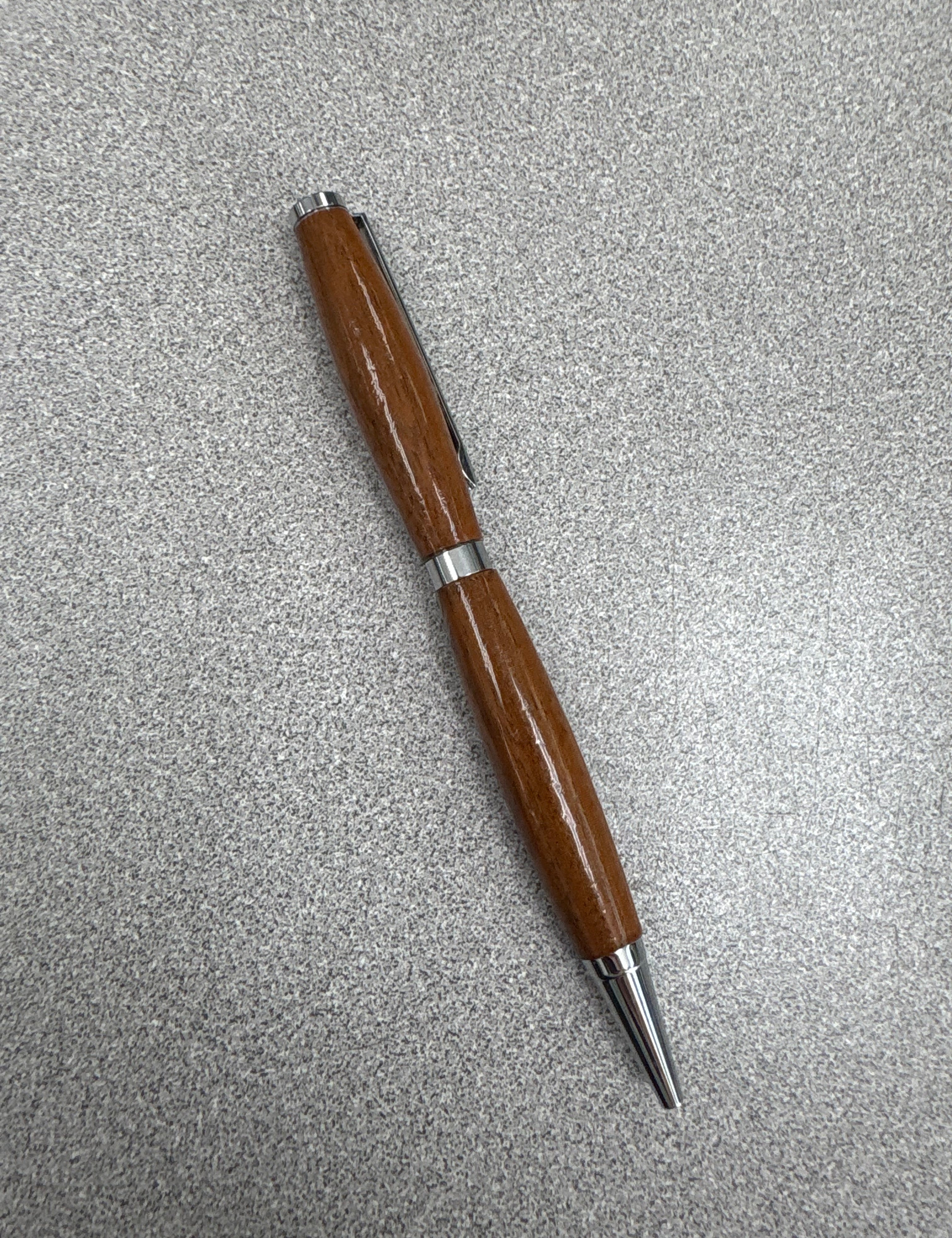 Wooden pen with silver accents on a gray surface