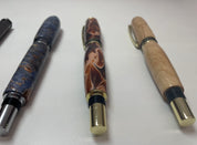 Three intricately designed pens on a white surface